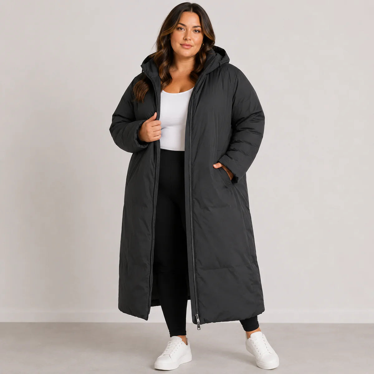 Woman wearing a long black coat against a plain background